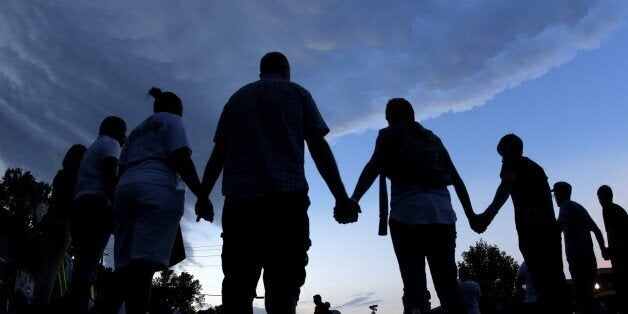 FILE - In this Aug. 20, 2014 fill photo people stand in prayer after march in Ferguson, Mo., to protest the shooting of Michael Brown. School officials concerned about students being waylaid by protests are asking a St. Louis County prosecutor to wait until classes are not in session to announce whether a white police officer will face charges for the fatal shooting of the unarmed black 18-year-old. The decision is expected by mid-November. (AP Photo/Charlie Riedel, File)