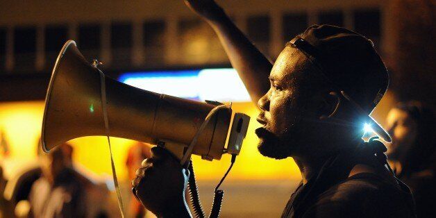 A protester uses a bullhorn as he takes part in a peaceful protest along a street in Ferguson, Missouri on August 19, 2014. Police lowered their profile on August 19, and refrained from using tear gas, to allow a more orderly night of protests in this St Louis suburb 10 days after the police shooting of an unarmed black teenager. AFP PHOTO / Michael B. Thomas (Photo credit should read Michael B. Thomas/AFP/Getty Images)