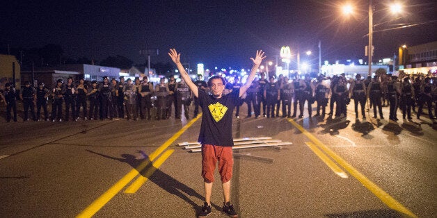 FERGUSON, MO - AUGUST 10: A demonstrator, marking the one-year anniversary of the shooting of Michael Brown, confronts police during a protest along West Florrisant Street on August 10, 2015 in Ferguson, Missouri. Mare than 100 people were arrested today during protests in Ferguson and the St. Louis area. Brown was shot and killed by a Ferguson police officer on August 9, 2014. His death sparked months of sometimes violent protests in Ferguson and drew nationwide focus on police treatment of black suspects. (Photo by Scott Olson/Getty Images)