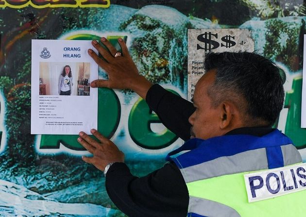 Un policier malaisien pose une affiche après la disparition de Nora Quoirin, le 9 août 2019 à Seremban en Malaisie