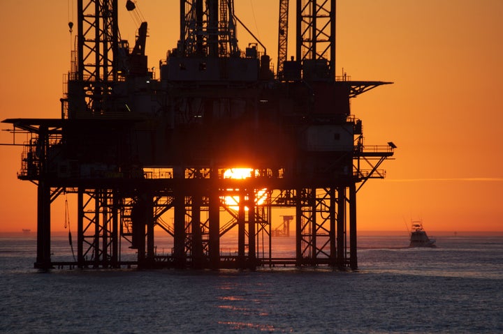 An oil and gas drilling rig at sunset in the Gulf of Mexico.