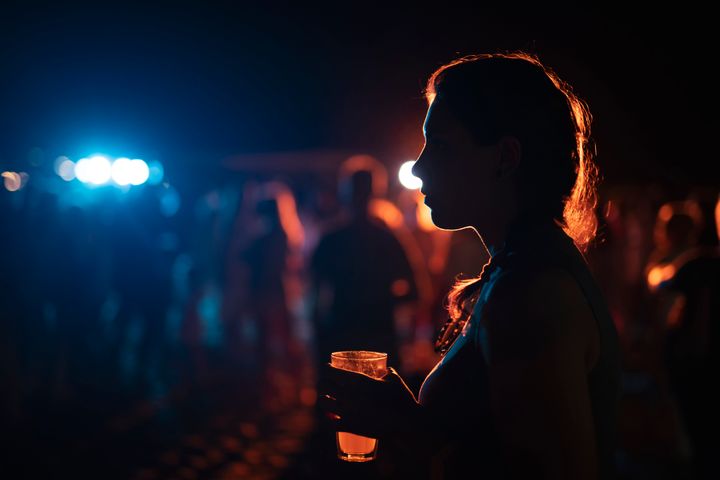 Silhouette of woman with cocktail on outdoor party.