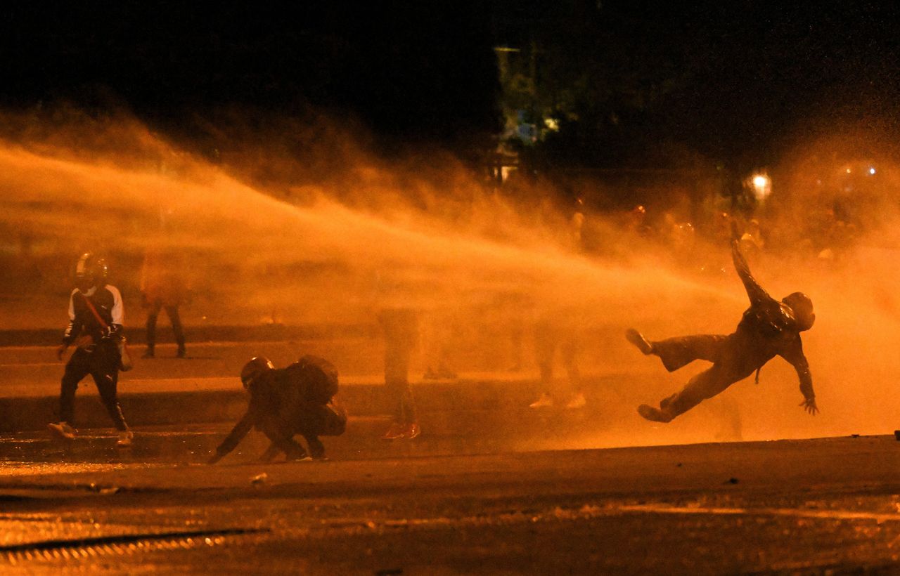TOPSHOT - A demonstrator falls as they are hit by water cannon during clashes with riot police amid ongoing protests against the government of Colombian President Ivan Duque in Bogota on June 12, 2021. - Dozens of people have been killed in protests that erupted around the country on April 28, initially against a tax hike that would have mostly affected the middle classes, but which have morphed into a major anti-government movement. (Photo by Juan BARRETO / AFP) (Photo by JUAN BARRETO/AFP via Getty Images)