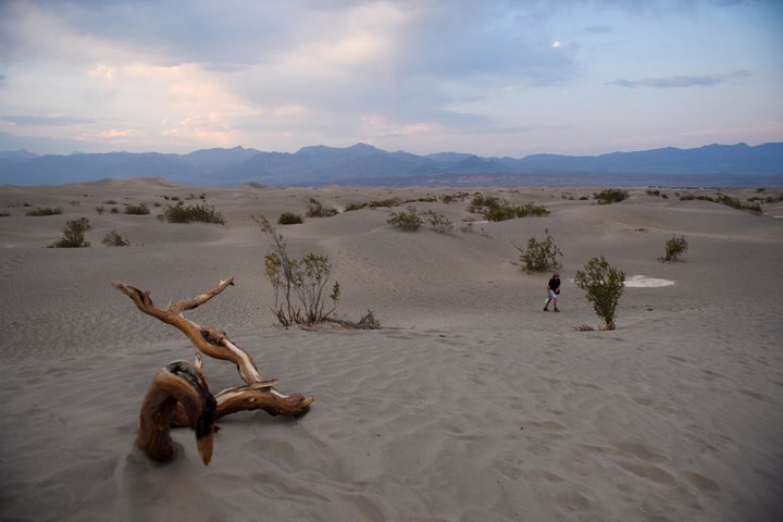 Visitors walk along sand dunes at sunset inside Death Valley National Park in June 17, 2021 in Inyo County, California. - Much of the western United States is braced for record heat waves this week, with approximately 50 million Americans placed on alert on June 15 for "excessive" temperatures, which could approach 120 degrees Fahrenheit (50 degrees Celsius) in some areas. The National Park Service warns of extreme summer heat, urging tourists to carry extra water and "travel prepared to survive" in the hottest, lowest, and driest national park featuring steady drought and extreme climates. (Photo by Patrick T. FALLON / AFP) (Photo by PATRICK T. FALLON/AFP via Getty Images)