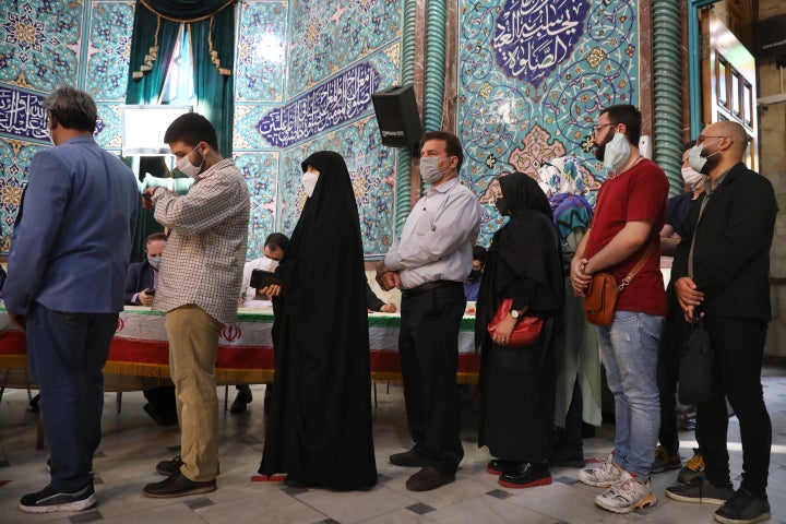 Voters queue at a polling station during the presidential elections in Tehran, Iran, Friday, June 18, 2021. Iranians voted Fr