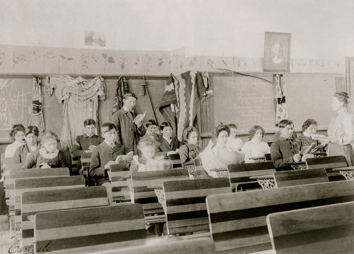 Students are seen reading in a classroom at the Indian Industrial School, in Carlisle, Pennsylvania, in 1901. The boarding school was government-run for Native American children.