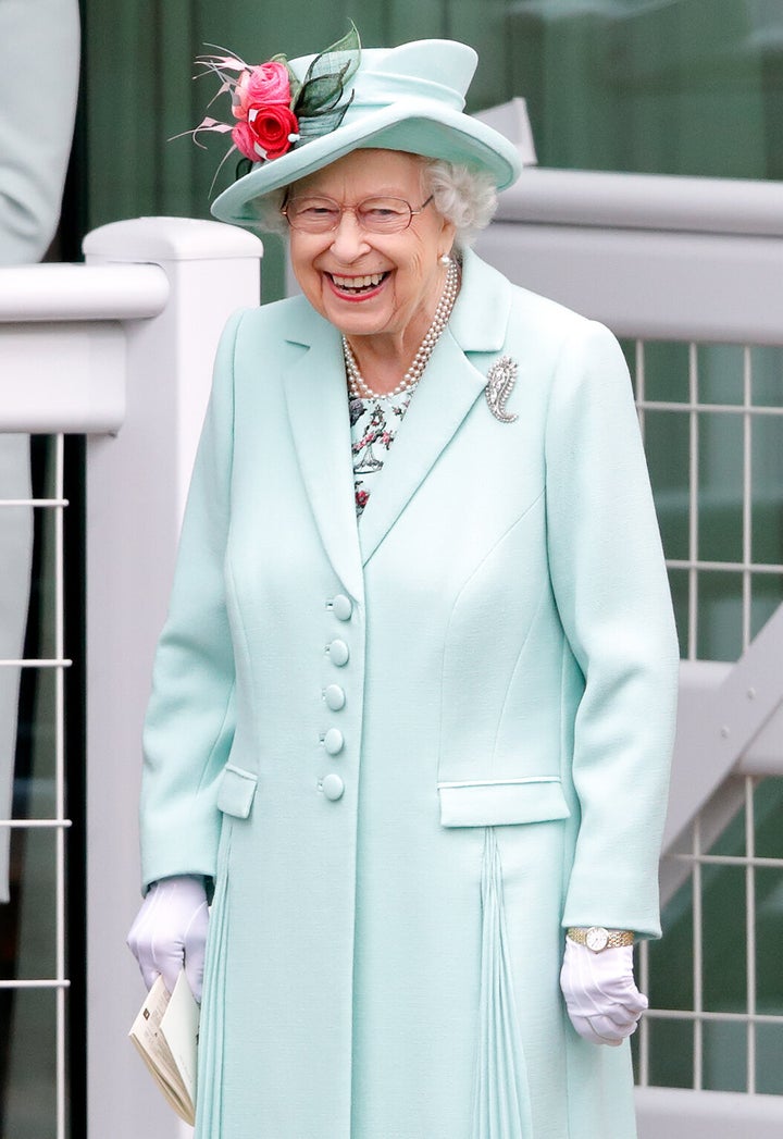 Queen Elizabeth II, wearing her Cartier diamond Palm Leaf Brooch, which belonged to Queen Elizabeth, the Queen Mother) holds 