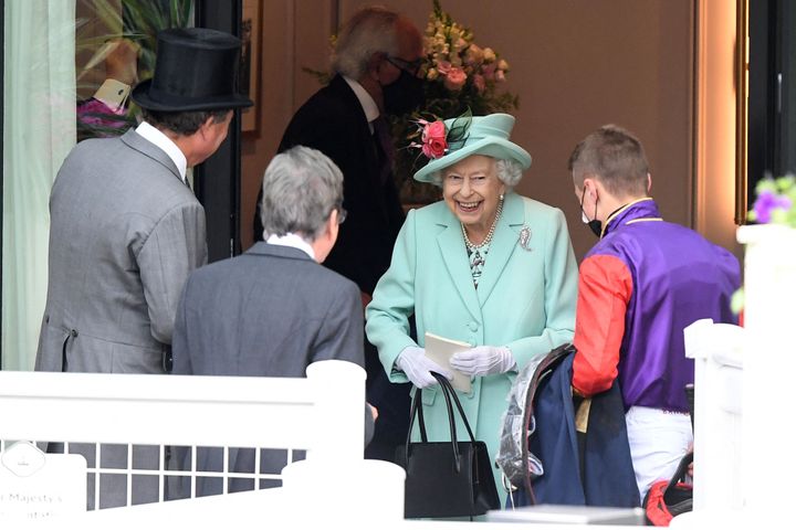 The queen smiles as she meets a jockey on the fifth day of the Royal Ascot horse racing meet. Royal Ascot reopened its doors to 12,000 racing fans a day but the coronavirus will still take a significant financial toll on the event. 