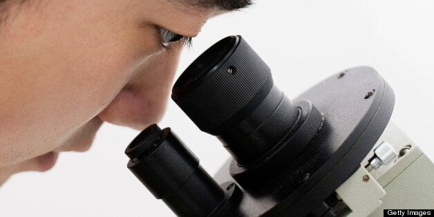 close up of man's eyes looking through microscope