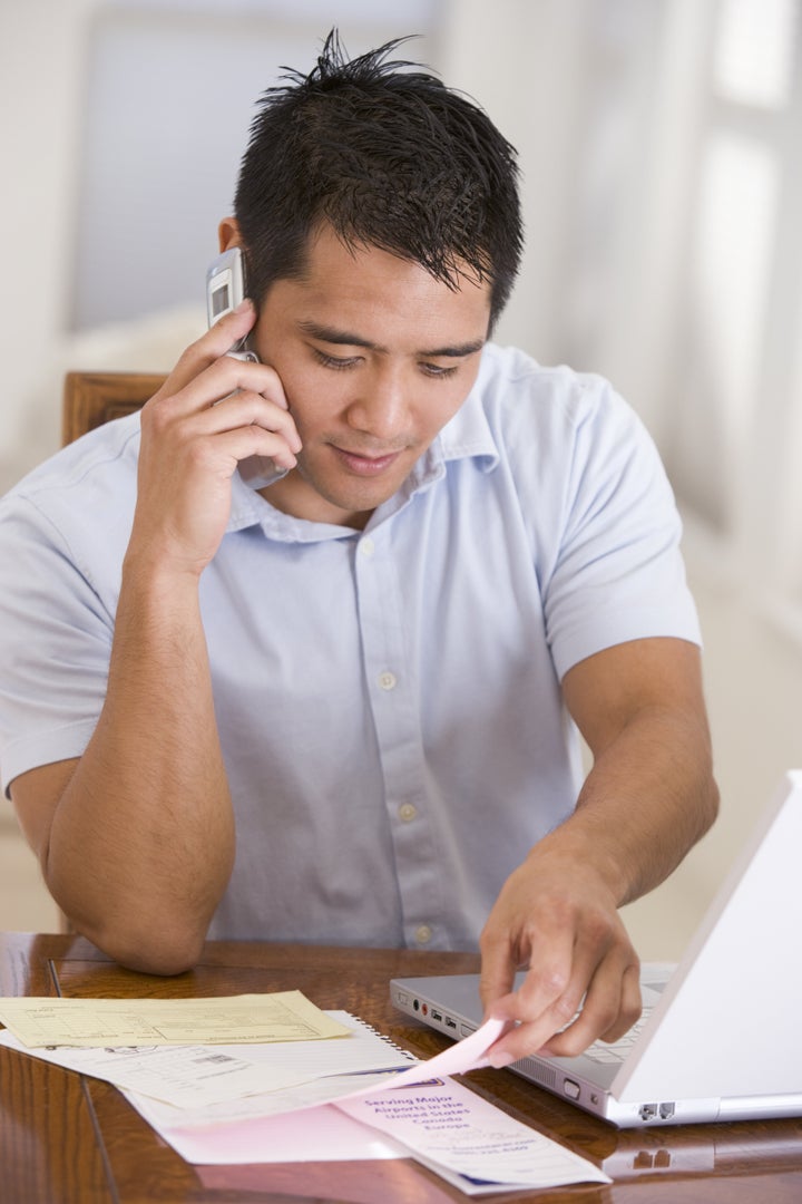 Man in dining room on cellular phone using laptop