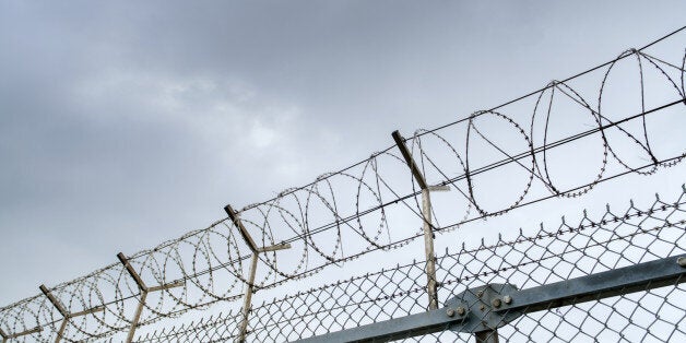 wired fence with barbed wires on blue sky background