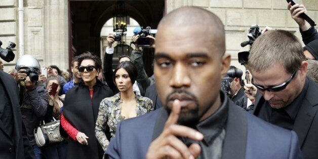 Kim Kardashian (C) pushes a stroller next to her partner Kanye West (front) and her mother Kris Jenner (2L) as they leave their hotel on May 23, 2014 in Paris. Hip hop star Kanye West and reality TV celebrity Kim Kardashian are expected to tie the knot this weekend, fuelling speculation about the wedding's location. AFP PHOTO/KENZO TRIBOUILLARD (Photo credit should read KENZO TRIBOUILLARD/AFP/Getty Images)