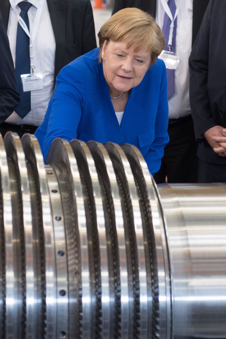 Φωτογραφία αρχείου. Η Άγκελα Μέρκελ κοιτάζει με έκδηλη περιέργεια μία τουρμπίνα σε εργοστάσιο της Siemens. (Photo by Sebastian Kahnert / dpa / AFP) / Germany OUT (Photo credit should read SEBASTIAN KAHNERT/DPA/AFP via Getty Images)