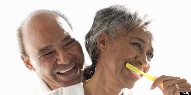 Senior couple embracing, woman brushing teeth, close-up