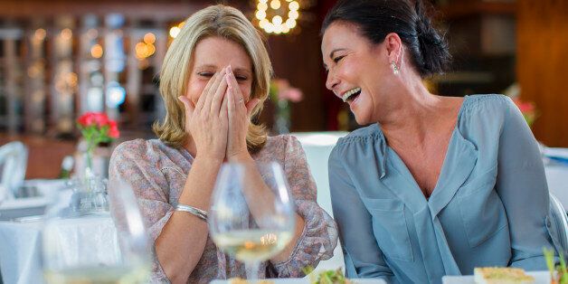 Two mature women laughing in restaurant