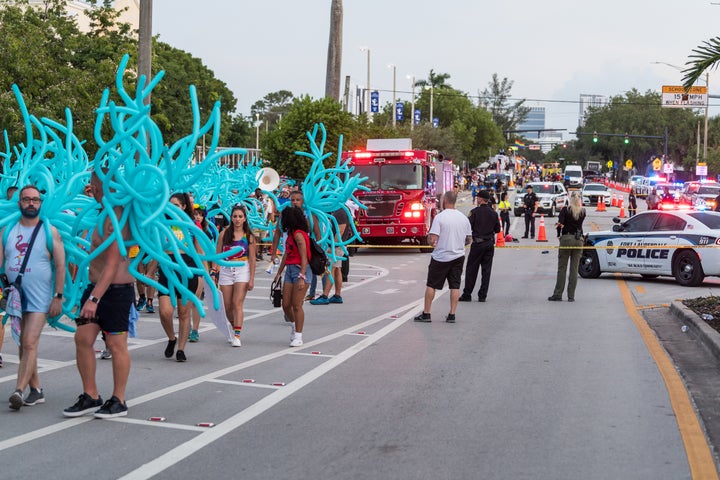 Parade participants walk away as police investigate the scene where a pickup truck drove into a crowd of people at a Pride pa
