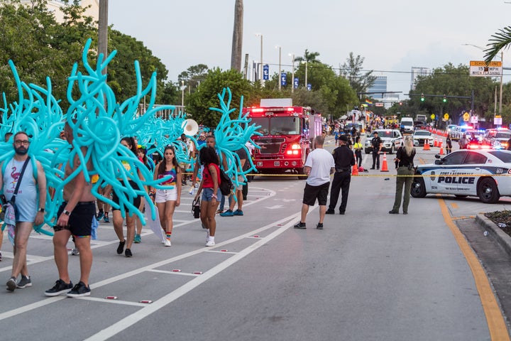 Parade participants walk away as police investigate the scene where a pickup truck drove into a crowd of people at a Pride parade in Wilton Manors, Florida. 