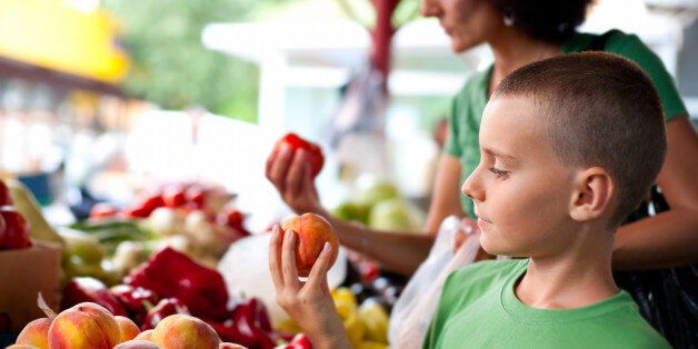 Cute boy with his mother buying fresh vegetables at the farmer's market