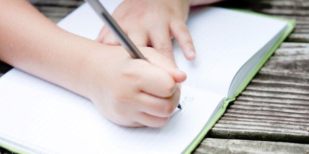 Hands of a young child, writing in their journal