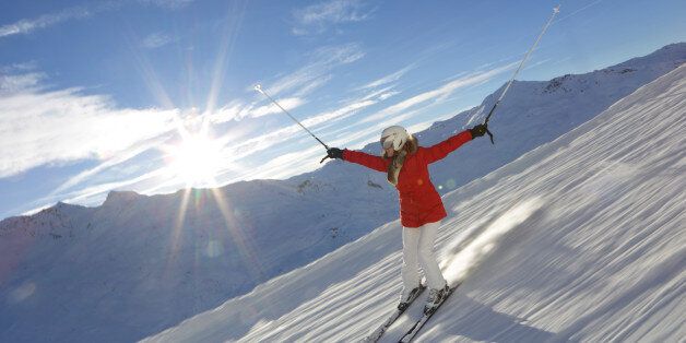 Woman skiing downhill, blue sky, sun shining
