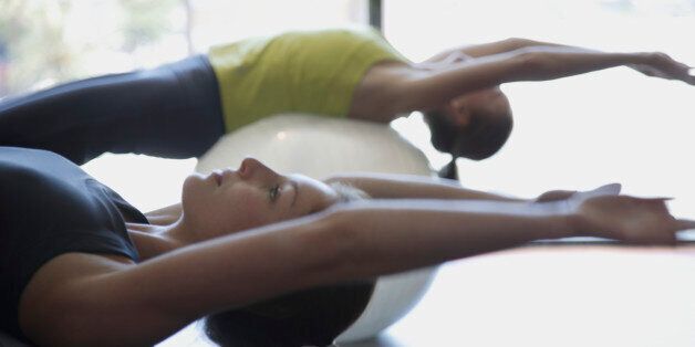 Two woman practicing Pilates on balls
