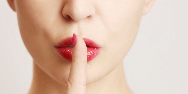 Woman holding her finger to her lips in a gesture for silence.