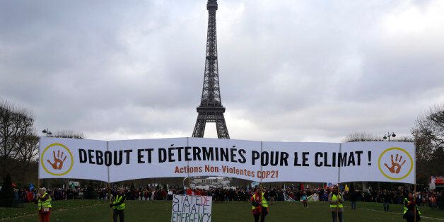Activists hold a banner reading "Standing and decided for Climate" during a demonstration near the Eiffel Tower, in Paris, Saturday, Dec.12, 2015 during the COP21, the United Nations Climate Change Conference. As organizers of the Paris climate talks presented what they hope is a final draft of the accord, protesters from environmental and human rights groups gather to call attention to populations threatened by rising seas and increasing droughts and floods. (AP Photo/Matt Dunham)