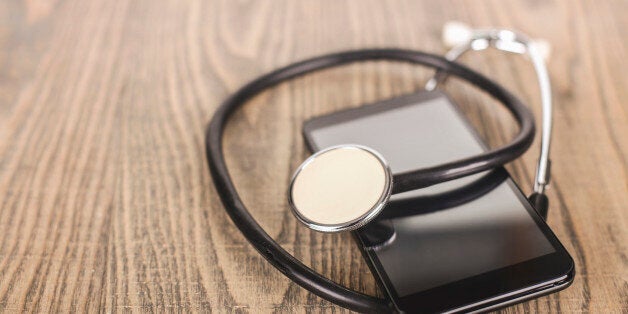 Modern smartphone with a stethoscope on a wooden background (repairing or virus protection concept).