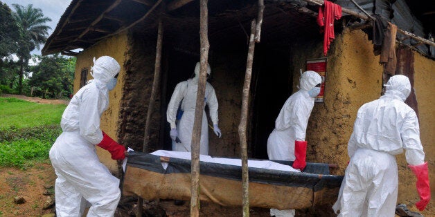 Hearth workers carry the body of a old man from his house as he is suspected of dying from the Ebola virus in the Siah Town area on the outskirts of Monrovia, Liberia, Friday, Oct. 31, 2014. The World Health Organization said this week that the rate of infection in Liberia appears to be falling but warned that the response effort must be kept up or the trend could be reversed. (AP Photo/ Abbas Dulleh)