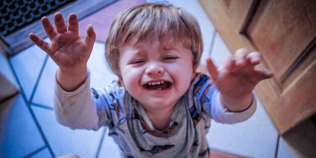 A photo looking down at an upset toddler - as if asking to be picked up.