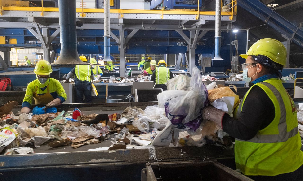 Workers remove non-recyclable plastics from cardboard at Republic Services in Anaheim, California, on April 15, 2021.