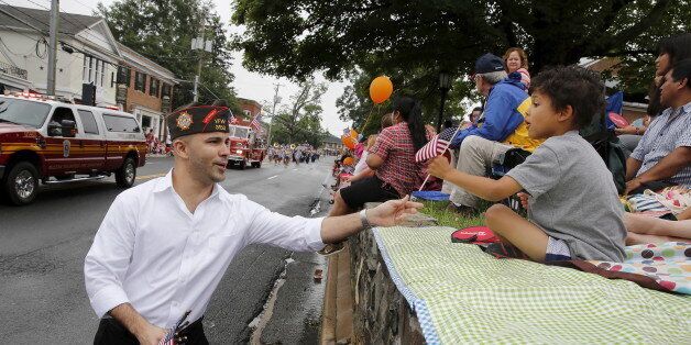 A member of the Veterans of Foreign Wars hands out U.S. flags to spectators at the Independence Day Parade in Fairfax, Virginia July 4, 2015. Americans marched in star-spangled parades, ran relay races, gathered for fireworks shows and crowned a new world hot dog eating champion as they celebrated Independence Day in traditional style on Saturday. REUTERS/Jonathan Ernst