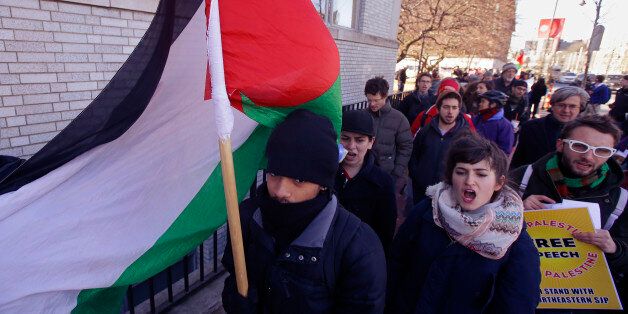 A Northeastern University student choosing not to give his name carries a Palestinian flag during a protest in support of Palestine after a Northeastern University student organization, Students for Justice in Palestine was "temporarily suspended for multiple violations of university policy over an extended period of time," according to a university statement in Boston, Tuesday, March 18, 2014. (AP Photo/Stephan Savoia)