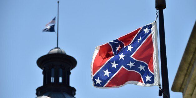 The South Carolina and US flags are seen flying at half-staff behind the Confederate flag erected in front of the State Congress building in Columbia, South Carolina on June 19, 2015. Police captured the white suspect in a gun massacre at one of the oldest black churches in Charleston in the United States, the latest deadly assault to feed simmering racial tensions. Police detained 21-year-old Dylann Roof, shown wearing the flags of defunct white supremacist regimes in pictures taken from social media, after nine churchgoers were shot dead during bible study on Wednesday. AFP PHOTO/MLADEN ANTONOV (Photo credit should read MLADEN ANTONOV/AFP/Getty Images)