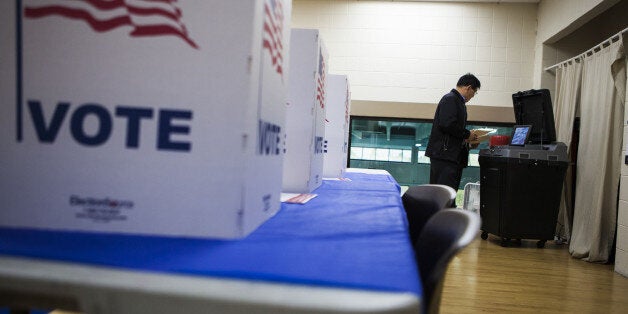 MCLEAN, VA - NOVEMBER 04 : A voter inserts his ballot into the collection machine during the US mid-term elections at a polling station in Mclean Virginia on November 4, 2014. (Photo by Samuel Corum/Anadolu Agency/Getty Images)