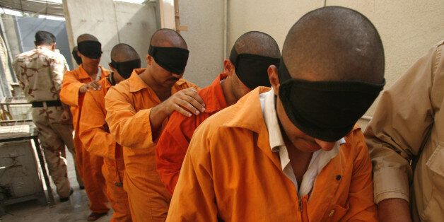 In this Aug. 11, 2007 file photo, blindfolded prisoners are taken for questioning at the Iraqi National Police Detention Center in the Kazimiyah neighborhood of North Baghdad, Iraq. Iraqi officials outraged by the abuse of prisoners at the U.S.-run Abu Ghraib prison are dealing with a prison scandal of their own as allegations continue to surface about years of torture and mistreatment inside Iraq's own lockups. (AP Photo/Petr David Josek, File)