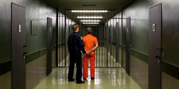 A prison guard leading a prisoner along a corridor