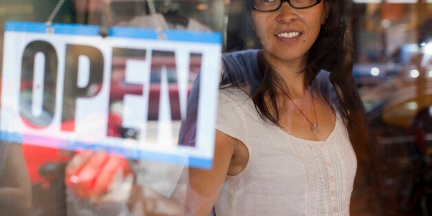Woman turing open sign at store.