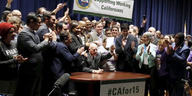 California Governor Jerry Brown (C) signs a bill hiking California's minimum wage to $15 by 2023 in Los Angeles, California, United States, April 4, 2016. REUTERS/Lucy Nicholson