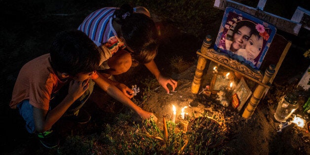 TACLOBAN, LEYTE, PHILIPPINES - NOVEMBER 01: Two young children tend to the grave of a loved one killed in the aftermath of Typhoon Haiyan at the mass grave site on the grounds of the San Joaquin Parish during All Saints Day on November 1, 2014 in Tacloban, Leyte, Philippines. Filipinos descend on cemetaries all across the country to tend to the graves of loved ones on November 1-2 marking All Saints day and All Souls day. Residents of Leyte are preparing for the 1-year anniversary since Super Typhoon Yolanda struck the coast on November 8, 2013, leaving more than 6000 dead and many more homeless. (Photo by Chris McGrath/Getty Images)