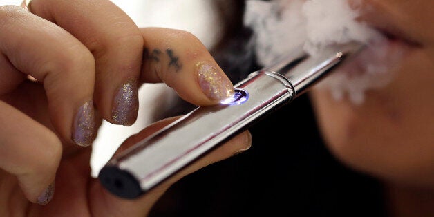 An employee poses for a photograph smoking a V-Revolution e-cigarette inside the company's store in London, U.K., on Wednesday, Oct. 16, 2013. The U.S. Food and Drug Administration is set to decide this month whether to lump e-cigarettes in with conventional smokes as part of its oversight of the $90 billion U.S. tobacco market. Photographer: Chris Ratcliffe/Bloomberg via Getty Images