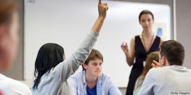 students in a classroom in a further education college, with one of them putting her hand up to ask a question