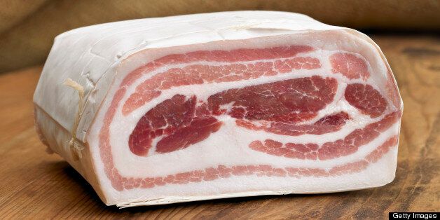 Pancetta, shot close up on wooden surface. This piece of meat is used in many Italian dishes. Studio shot, horizontal frame.