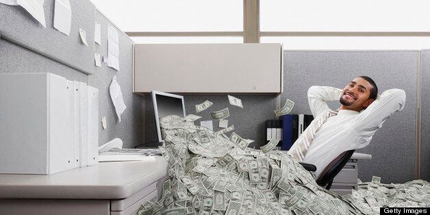 Hispanic businessman in cubicle covered in one dollar bills