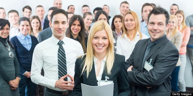 Young attractive smiling business woman standing in front of group of business people