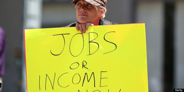 OAKLAND, CA - JULY 11: A protestor holds a sign during a demonstration against unemployment benefit cuts on July 11, 2012 in Oakland, California. Dozens of protestors with the group Union of Unemployed Workers staged a demonstration to protest cuts in unemployment benefits. (Photo by Justin Sullivan/Getty Images)