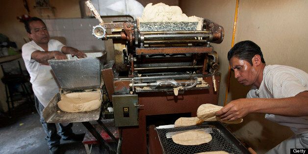 A worker collects tortillas coming out of machine in a tortilla bakery at the Zona Rosa in Mexico City, Mexico, on Monday, April 1, 2013. Mexico?s consumer confidence index rose to a four-year high in January and the economy will grow 3.5 percent this year, according to the median estimate of economists surveyed by Bloomberg, its fourth consecutive year of expansion of greater than 3 percent. Photographer: Susana Gonzalez/Bloomberg via Getty Images