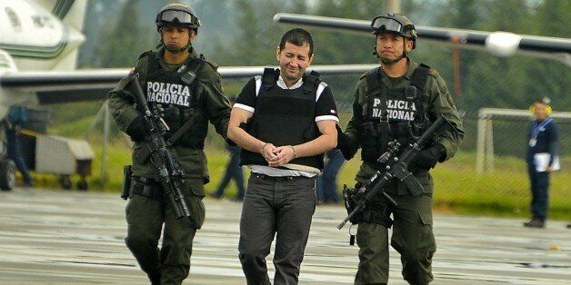 Colombian drug trafficker Daniel Barrera (C) aka 'El Loco' is escorted by policemen before being deported to the United States at the Antinarcotics Police Airport on July 9, 2013 in Bogota. Barrera is considered as Colombias most important drug lord of the past decade. AFP PHOTO/LUIS ACOSTA (Photo credit should read LUIS ACOSTA/AFP/Getty Images)