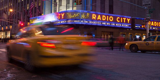 Taxis pass in front of Madison Square Garden Co.'s Radio City Music Hall in New York, U.S., on Tuesday, Feb. 4, 2014. The Madison Square Garden Co. is scheduled to release earnings data on Feb. 7. Photographer: Ron Antonelli/Bloomberg via Getty Images