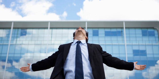 Businessman standing in front of building with arms outstretched